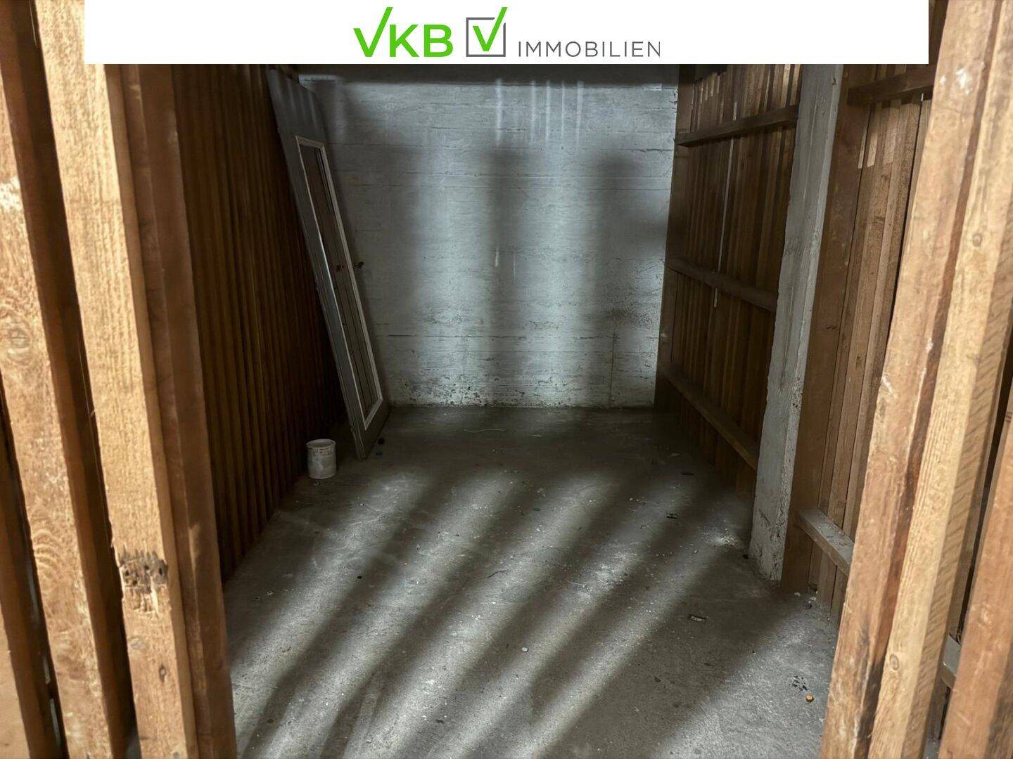 Geräumiger Kellerraum mit Betonboden und Holzabtrennungen, ideal als Lagerfläche.