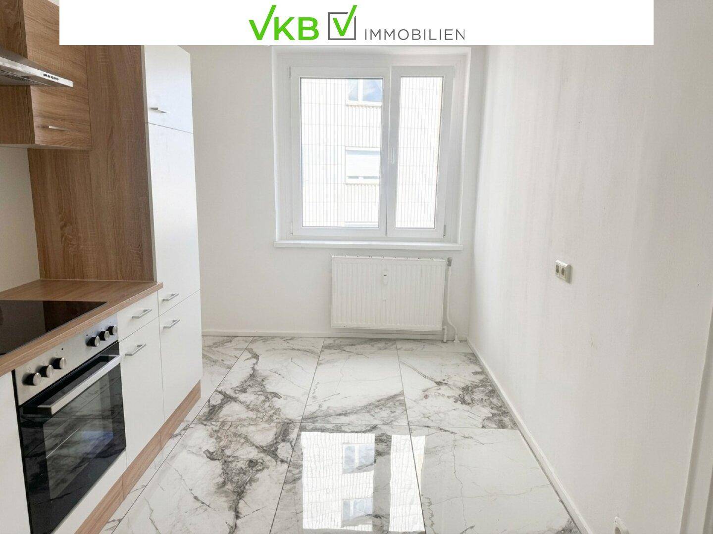 Leere Küche mit modernen Einbauschränken, Induktionskochfeld und Fliesenboden.