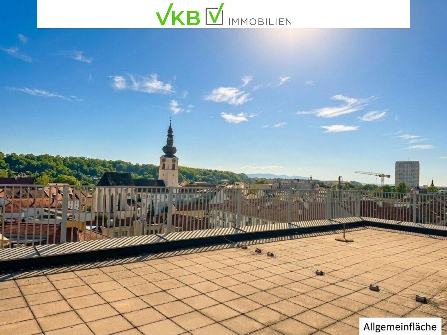 Große Dachterrasse mit Fliesenboden und Panoramablick über die Stadt.