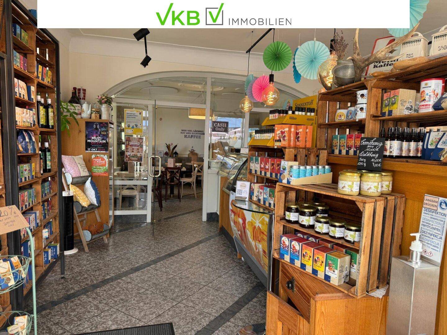 Verkaufsbereich mit Regalen voller Produkte, einer Theke und Blick in den Gastraum.