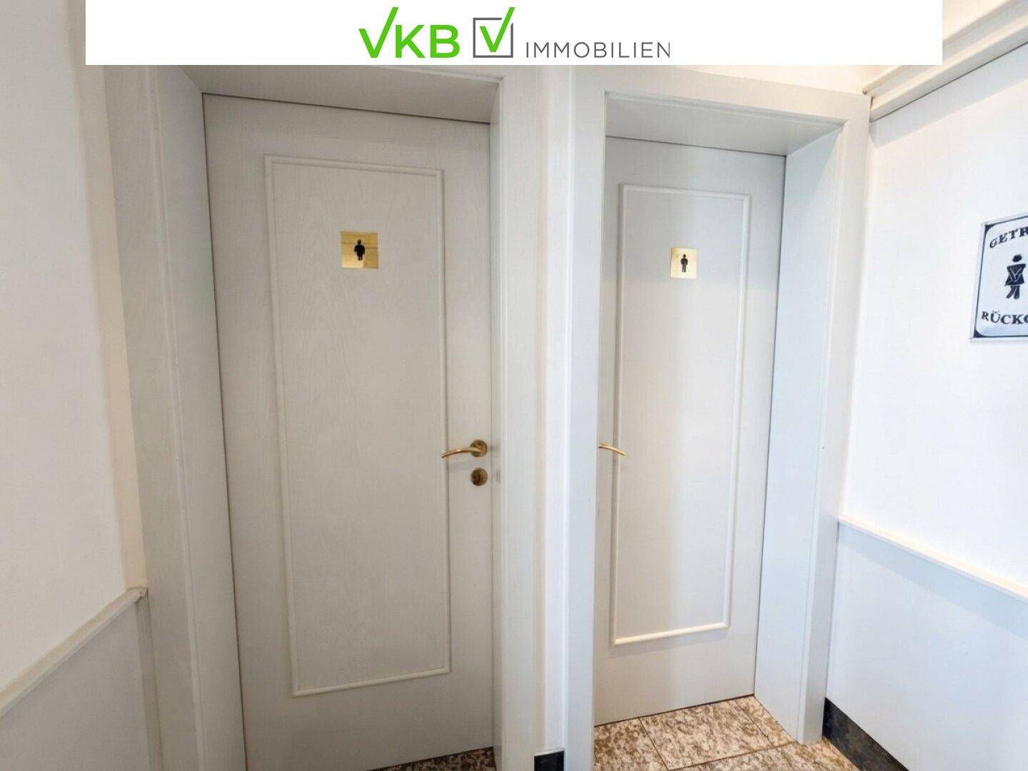 Zwei weiße Türen mit Piktogrammen, die zu den Toilettenräumen führen.