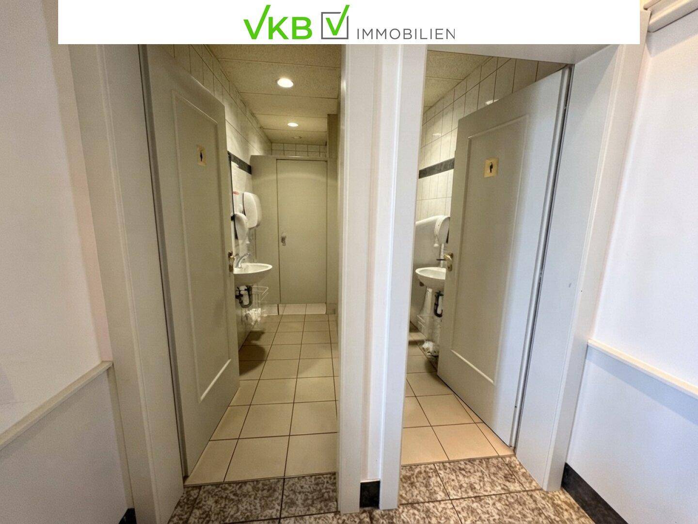Helle Toilettenräume mit Fliesenboden, Waschbecken und Spiegeln, getrennt für Damen und Herren.