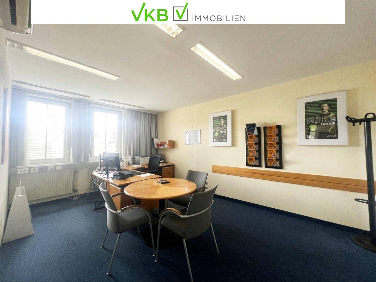 Helles Büro mit blauem Teppichboden, gelben Wänden und einem runden Besprechungstisch.