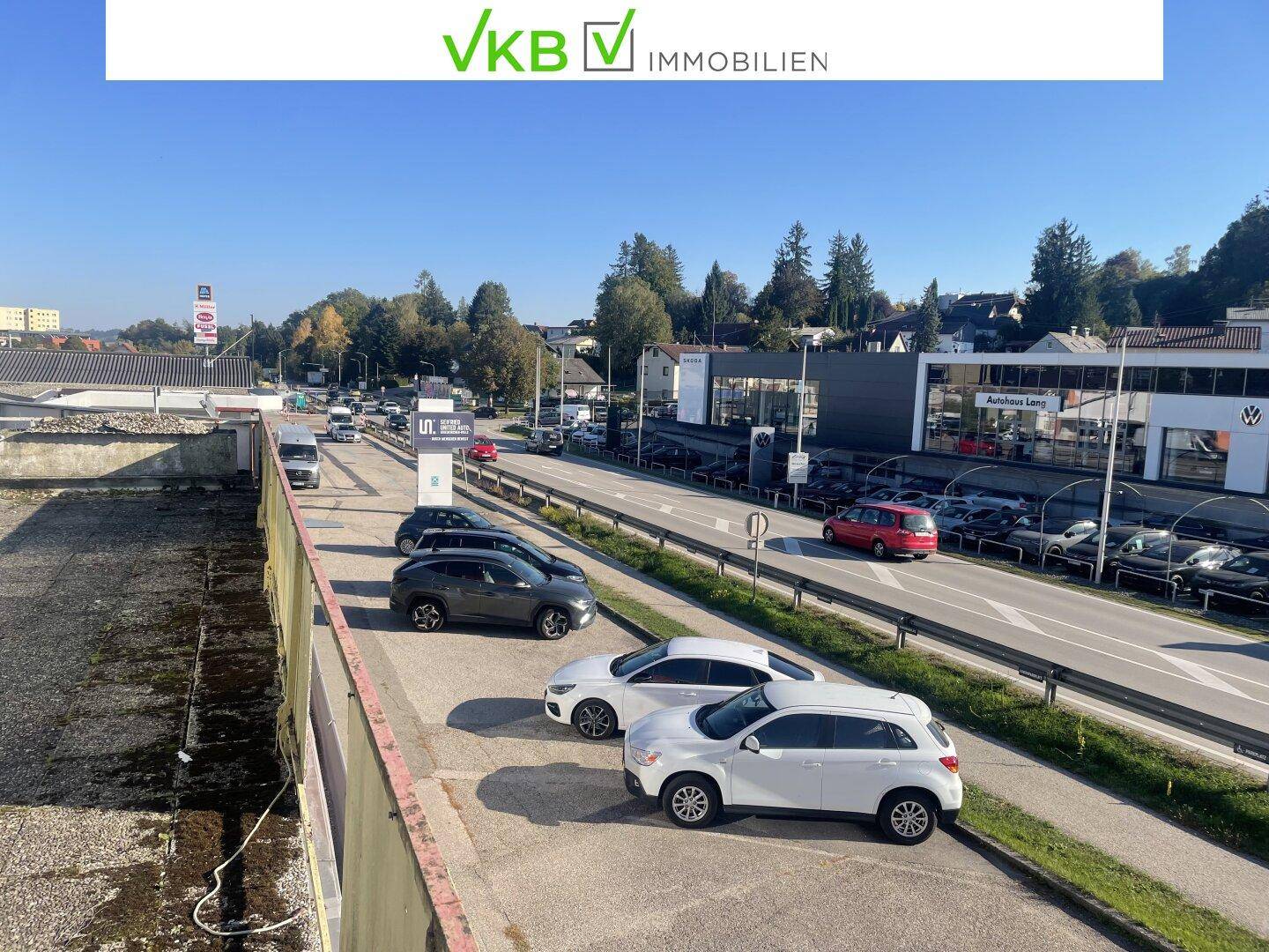 Weitläufiger Blick auf die Straße und angrenzende Gebäude mit geparkten Autos und Verkehr.