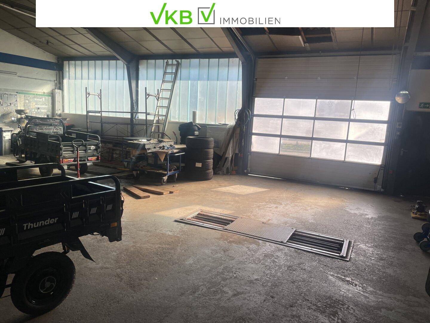 Geräumige Werkstatthalle mit Rolltor und Oberlichtern, ideal für industrielle Nutzung und Lagerung.