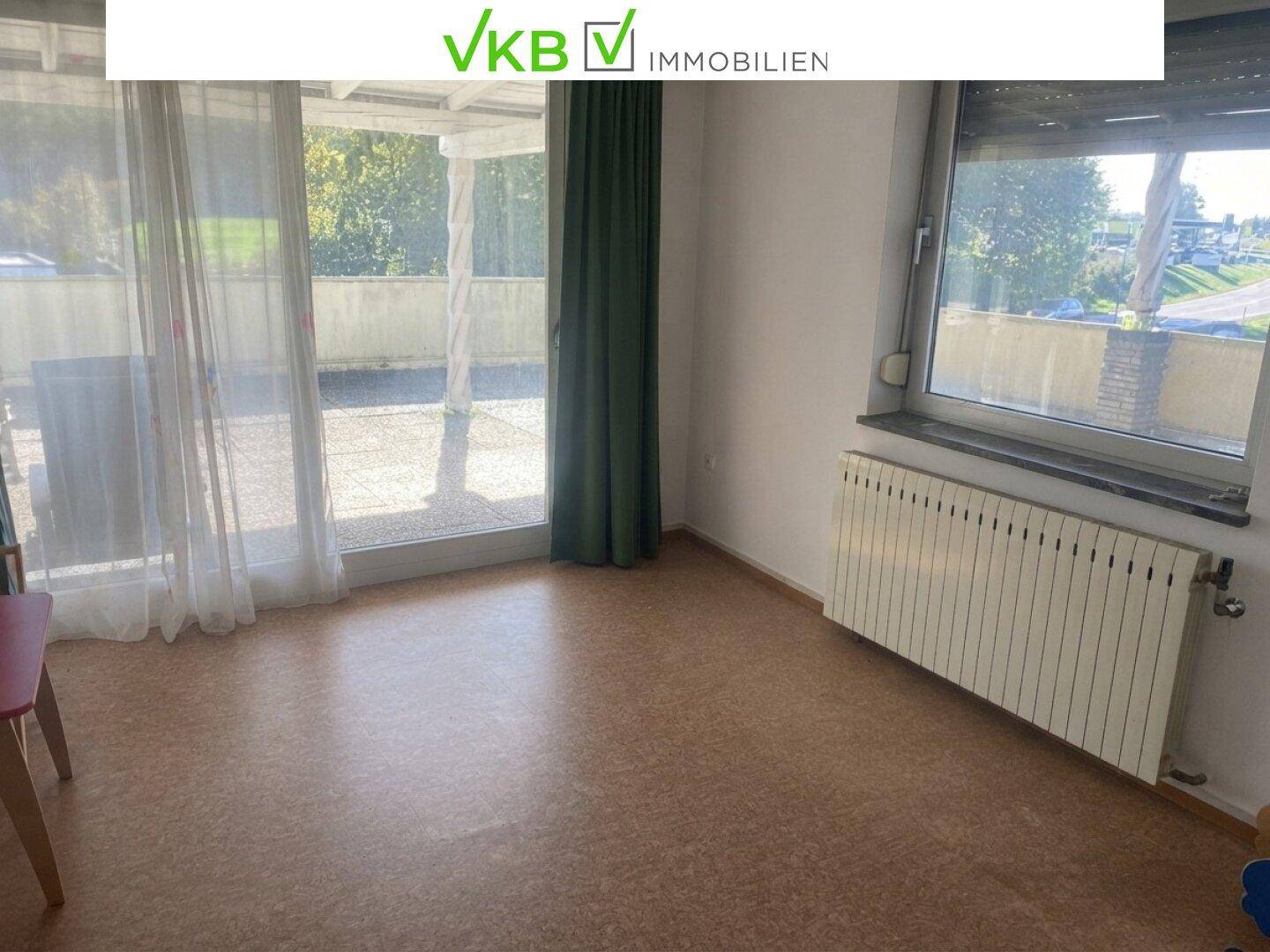 Heller Wohnraum mit Zugang zu einer Terrasse und einem großen Fenster, ausgestattet mit Heizkörper.