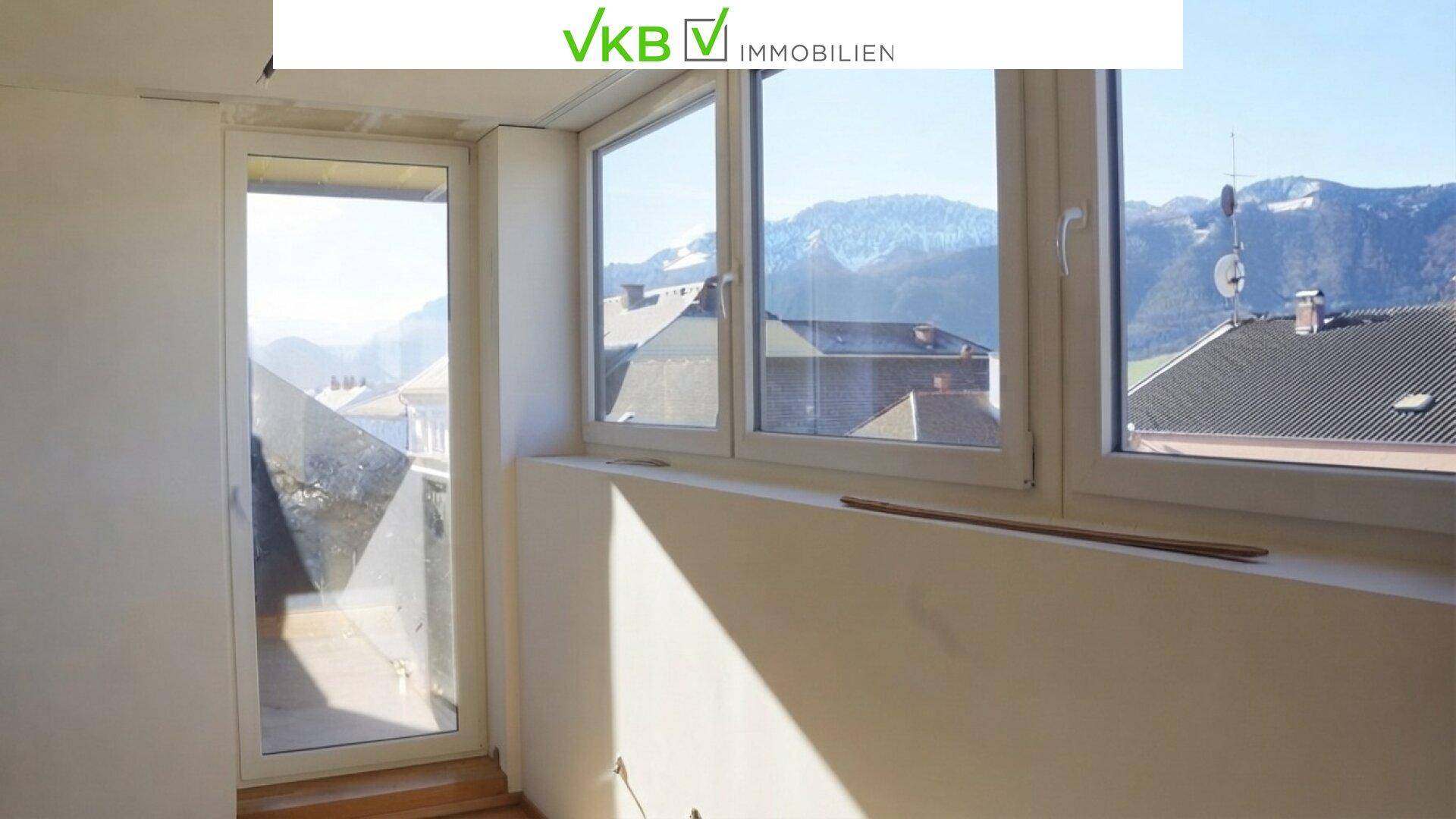 Heller Raum mit Zugang zu einem Balkon und weitem Blick auf die umliegende Bergwelt.