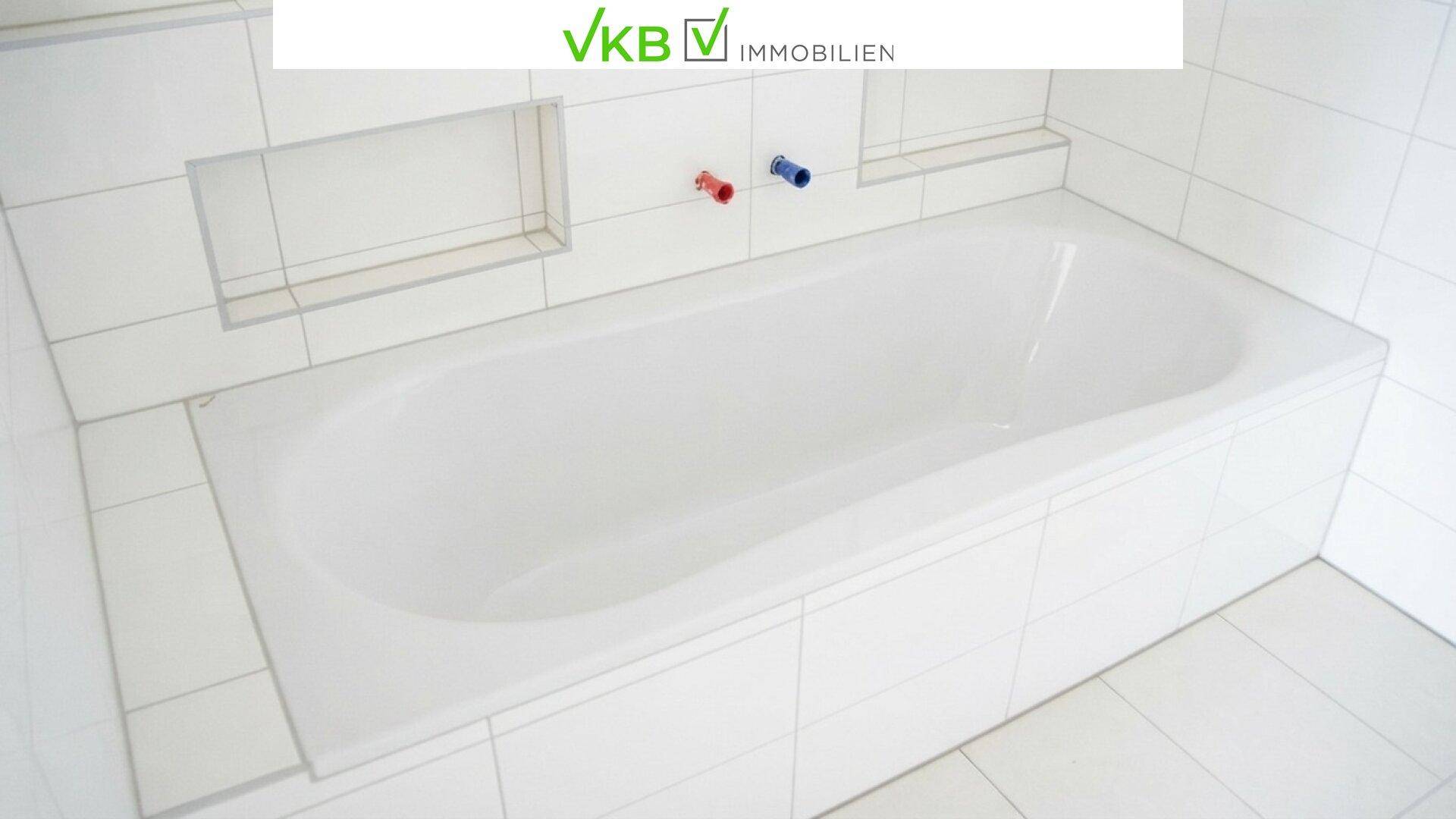 Weiß gefliestes Badezimmer mit einer eingebauten Badewanne und praktischen Nischen in der Wand.