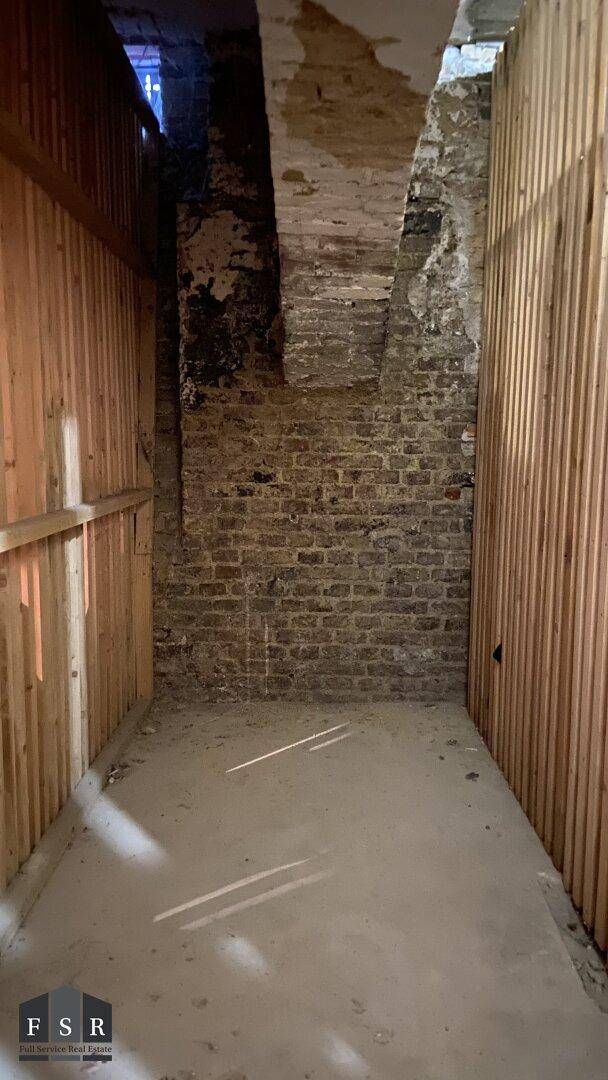 Unausgebauter Kellerraum mit unverputzten Ziegelwänden und Betonboden, ideal als Stauraum.