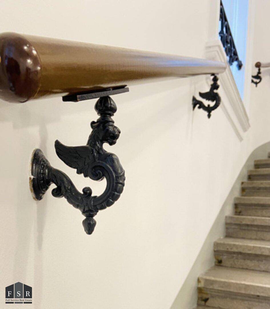Detailansicht eines kunstvoll verzierten Handlaufs im historischen Treppenhaus.
