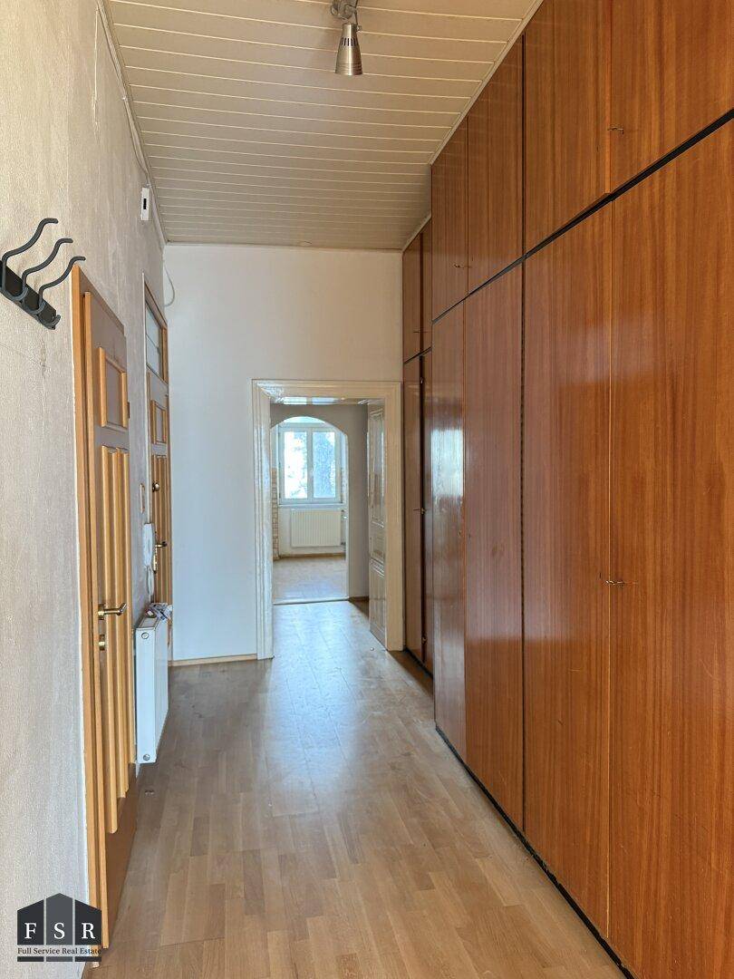 Langer Flur mit Einbauschränken aus Holz und Parkettboden, führt zu weiteren Räumen.