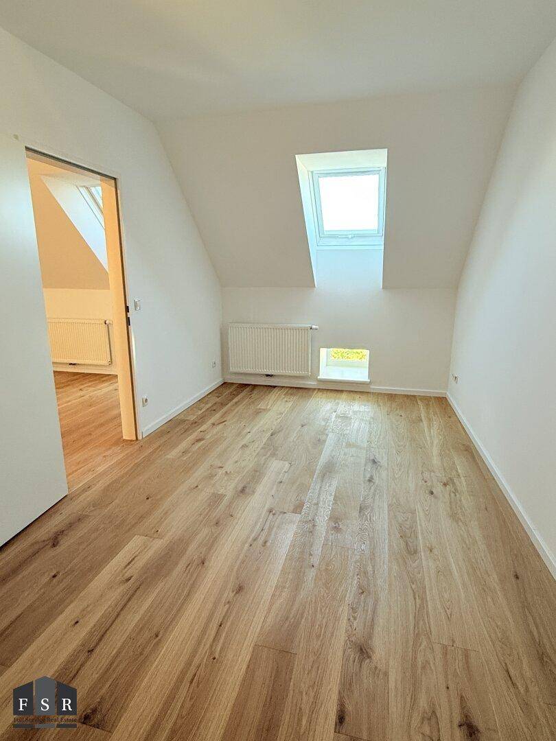 Ruhiges Schlafzimmer im Dachgeschoss mit Holzboden, Dachfenster und schrägen Wänden.