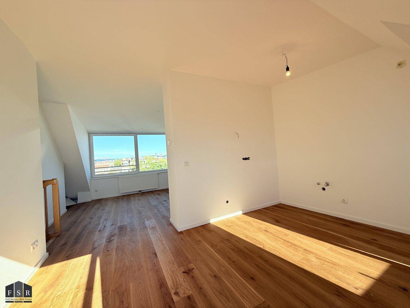 Geräumiger Wohnbereich mit Holzboden, der zu einem hellen Zimmer mit Stadtblick führt.