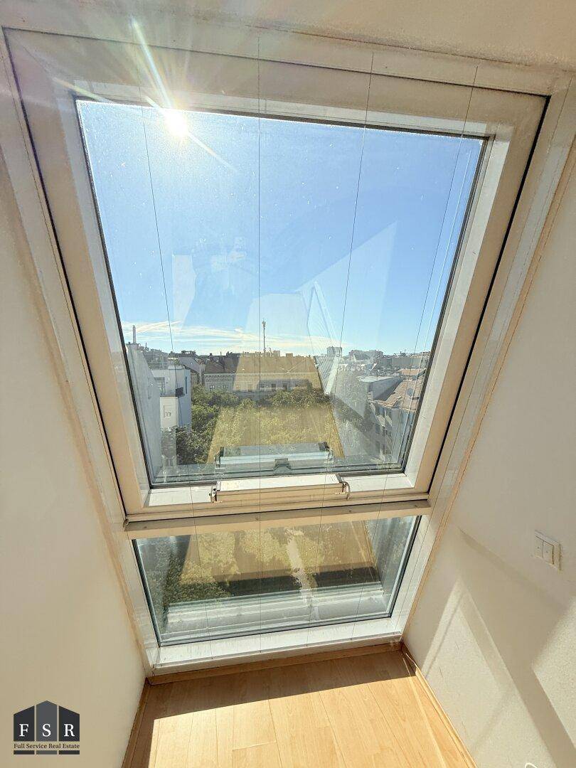 Großes Dachfenster mit weitem Blick über die Stadt, das viel Tageslicht in den Raum bringt.