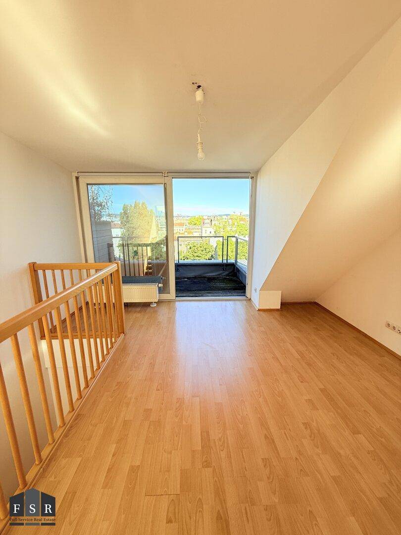 Geräumiger Wohnbereich mit Laminatboden, Dachschräge und direktem Zugang zum sonnigen Balkon.