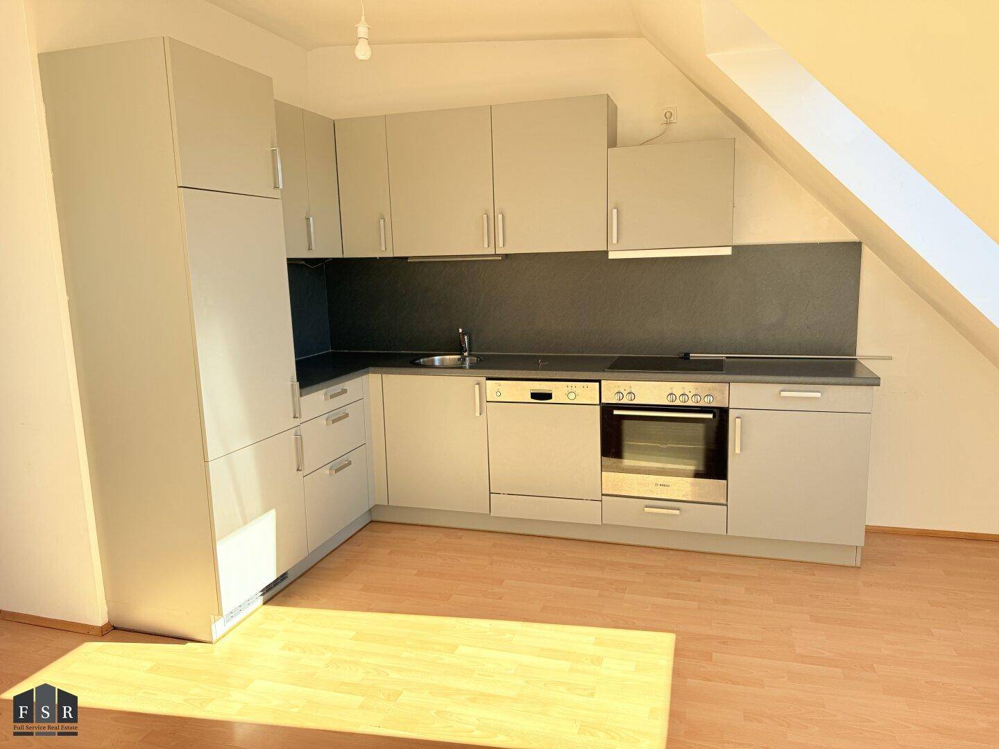 Moderne Einbauküche in Grau mit integrierten Geräten, Spüle und ausreichend Stauraum.