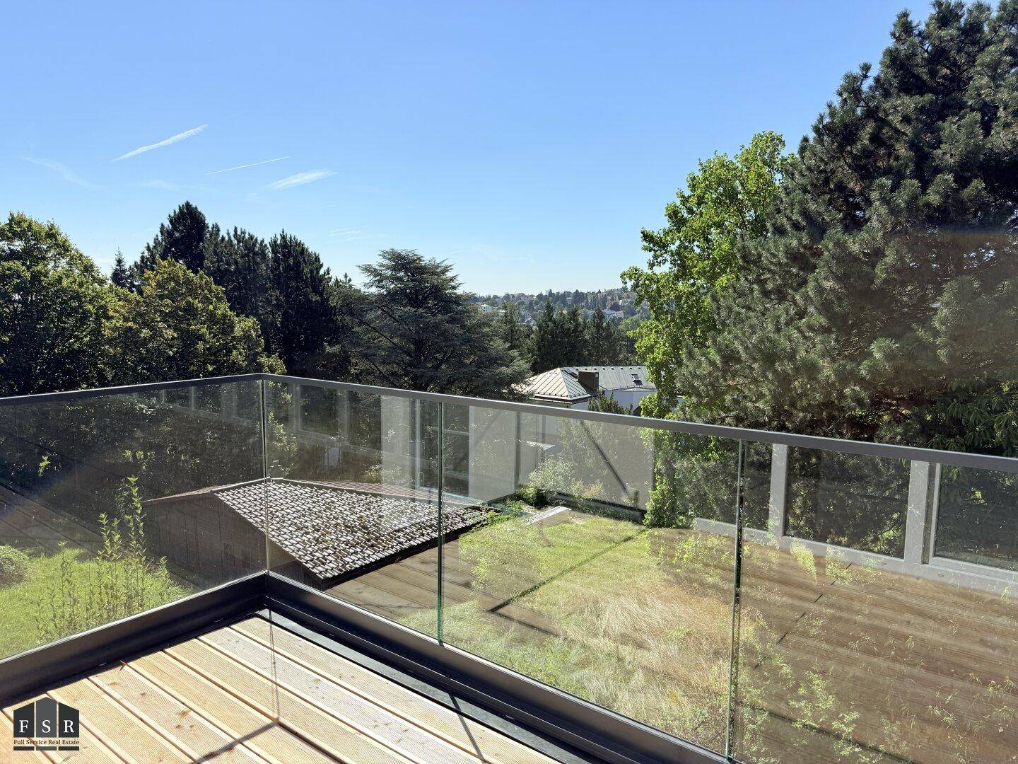 Panoramablick von der Terrasse mit Glasgeländer über die grüne Umgebung.