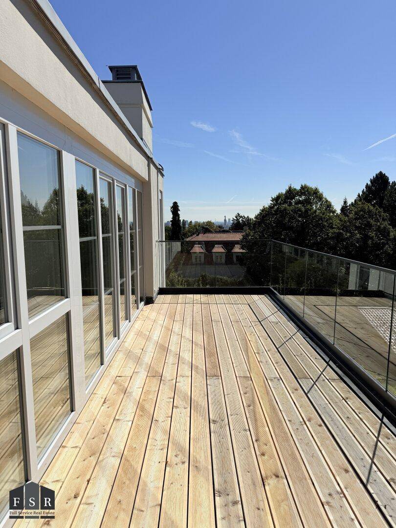 Weitläufige Holzterrasse mit Glasgeländer und Panoramablick über die Landschaft.