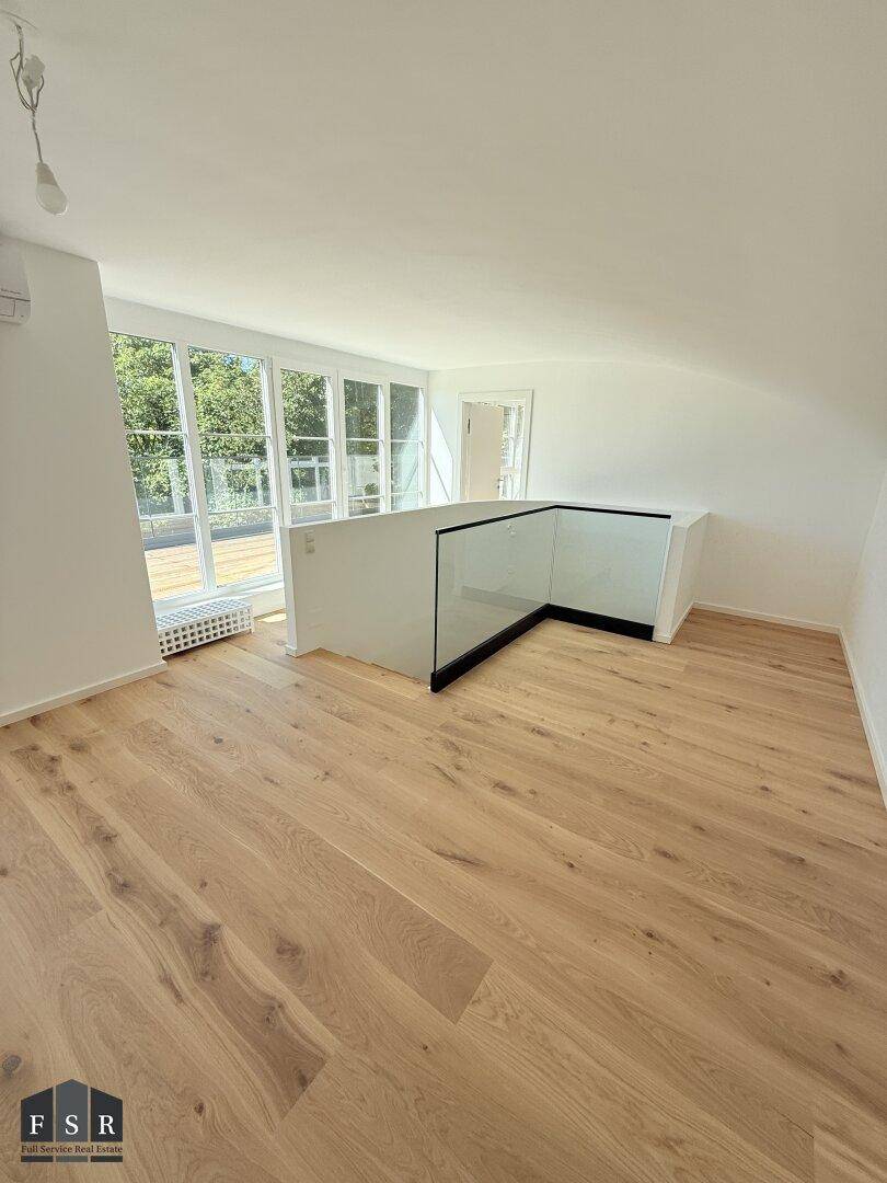 Geräumiger Dachgeschossbereich mit Holzboden, großen Fenstern und offener Galerie.