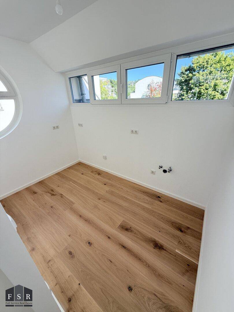 Kleiner, heller Raum mit Holzboden und Fenstern, ideal als Arbeitsbereich.