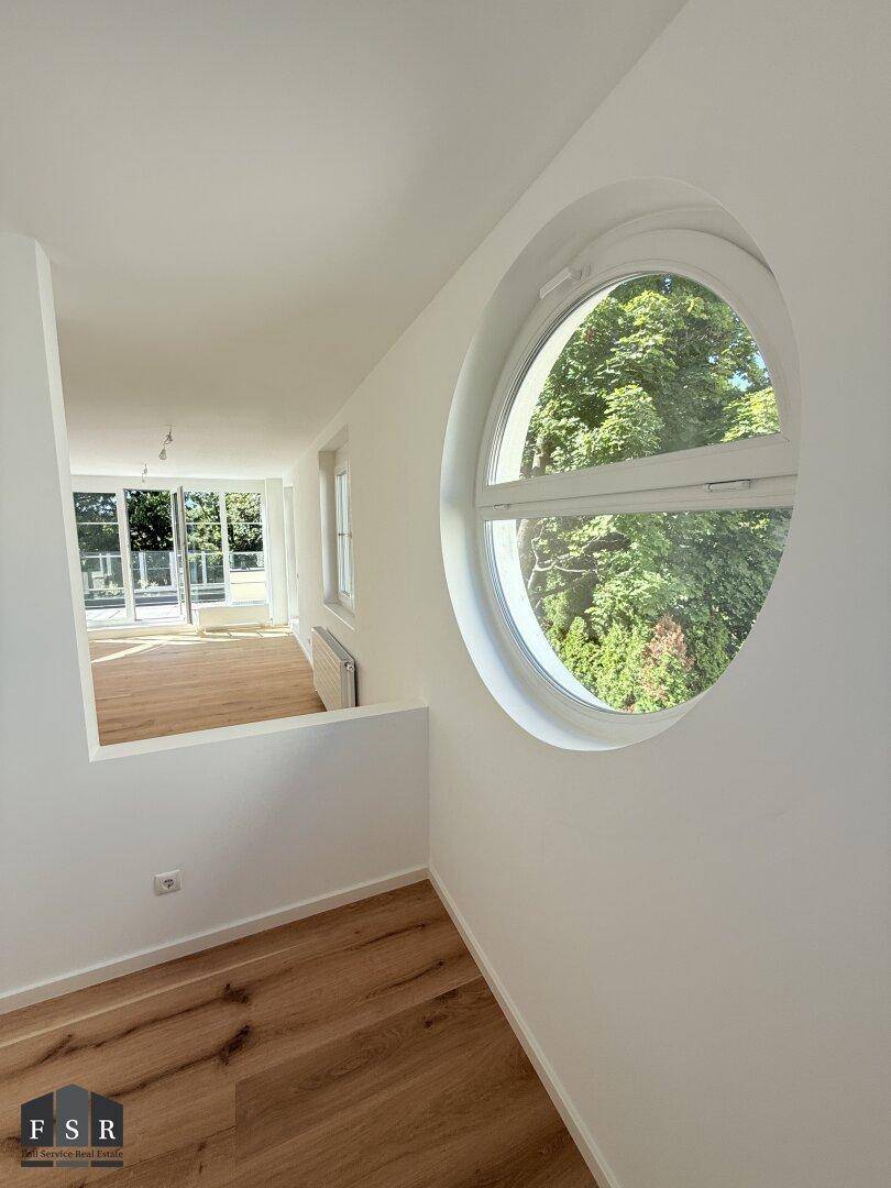 Heller Flur mit einzigartigem Rundfenster und Blick in den angrenzenden Wohnbereich.