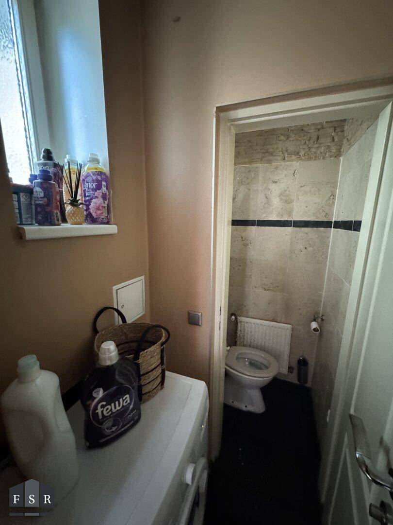 Praktischer Hauswirtschaftsbereich mit Waschmaschine und Zugang zu einer separaten Toilette.