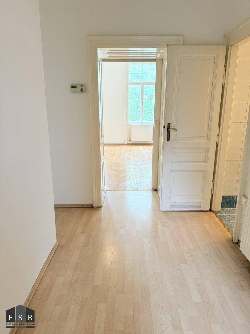 Heller Flur mit Laminatboden, weißen Türen und Zugang zu weiteren Räumen.