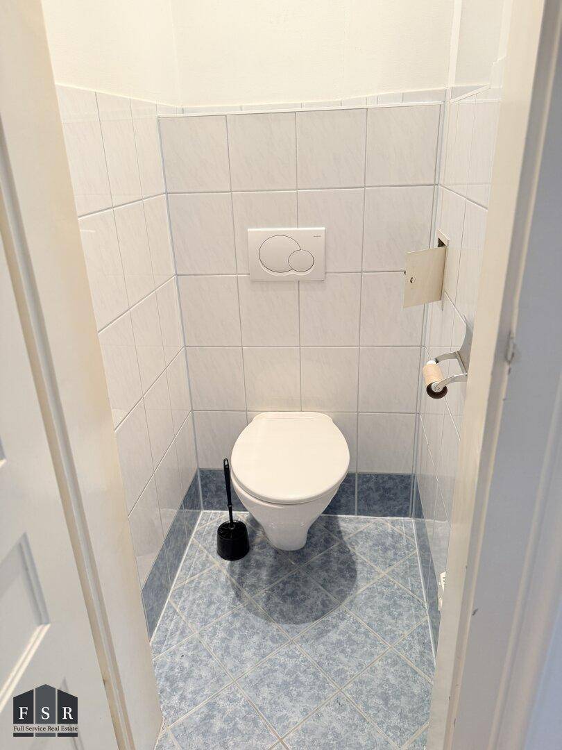 Kleines Gäste-WC mit blauen und weißen Fliesen und wandhängendem WC.