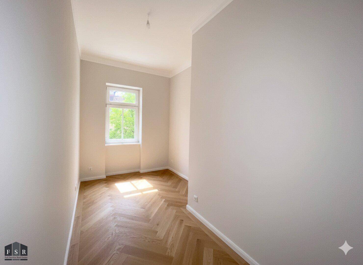 Kleiner, heller Raum mit Fischgrätparkett und einem Fenster, ideal als Schlaf- oder Arbeitszimmer.