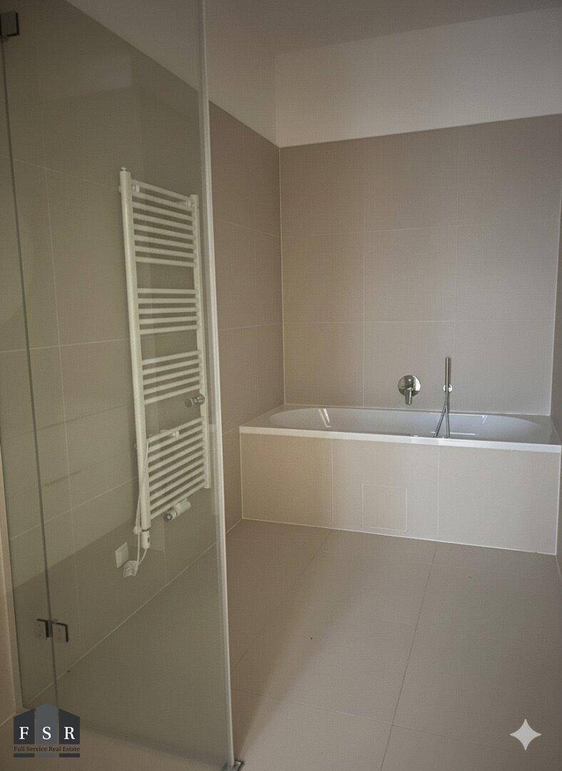 Modernes Badezimmer mit Badewanne, Duschbereich und beheiztem Handtuchhalter in neutralen Farben.