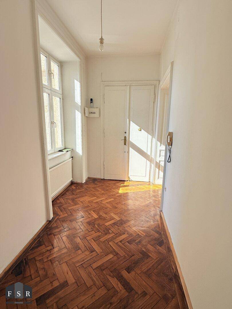 Eingangsbereich mit Fischgrätparkett, weiß gestrichenen Wänden und viel natürlichem Licht, einladend und hell.