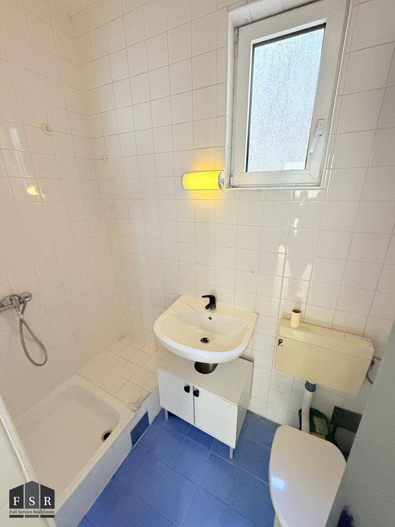 Funktionales Badezimmer mit Dusche, WC, Waschbecken und einem Fenster für Tageslicht.