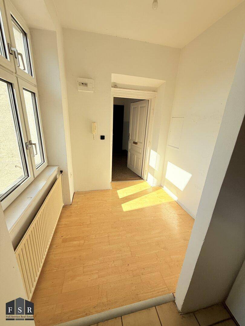 Heller Flurbereich mit Parkettboden, großem Fenster und viel Sonneneinstrahlung.
