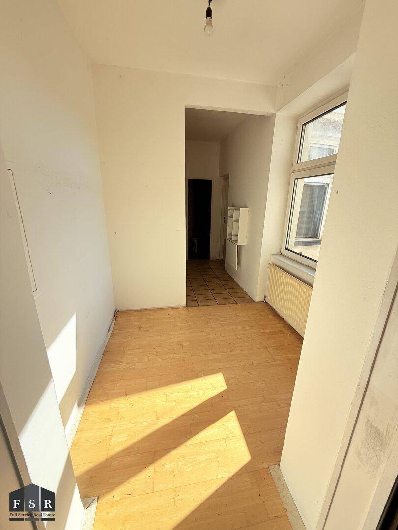 Kleiner, heller Raum mit Parkettboden und Fenster, ideal als Arbeitsbereich oder Flur.