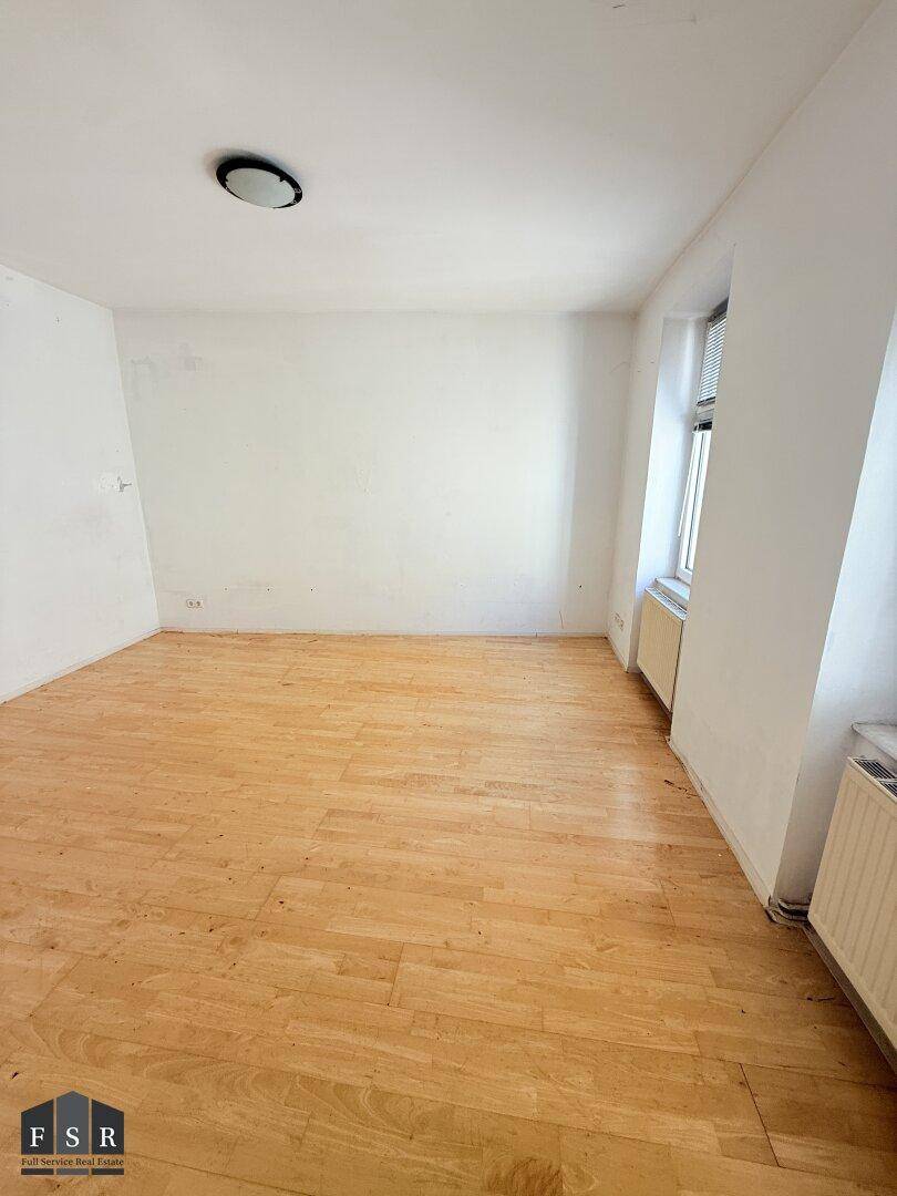 Heller Wohnraum mit Parkettboden und Fenster, bereit für neue Einrichtungsideen.