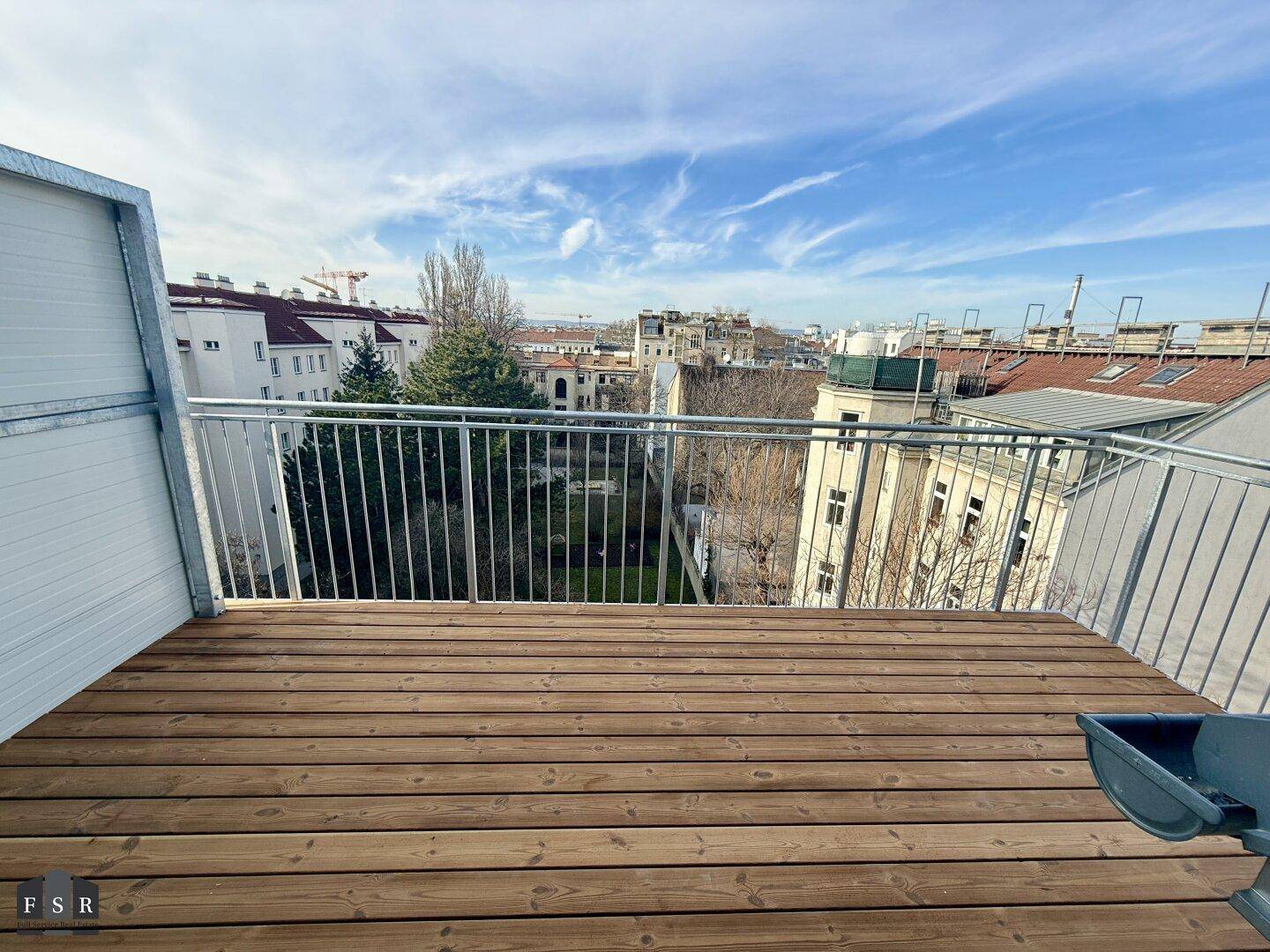 Sonniger Balkon mit Holzdielen und weitem Blick über die Stadt.