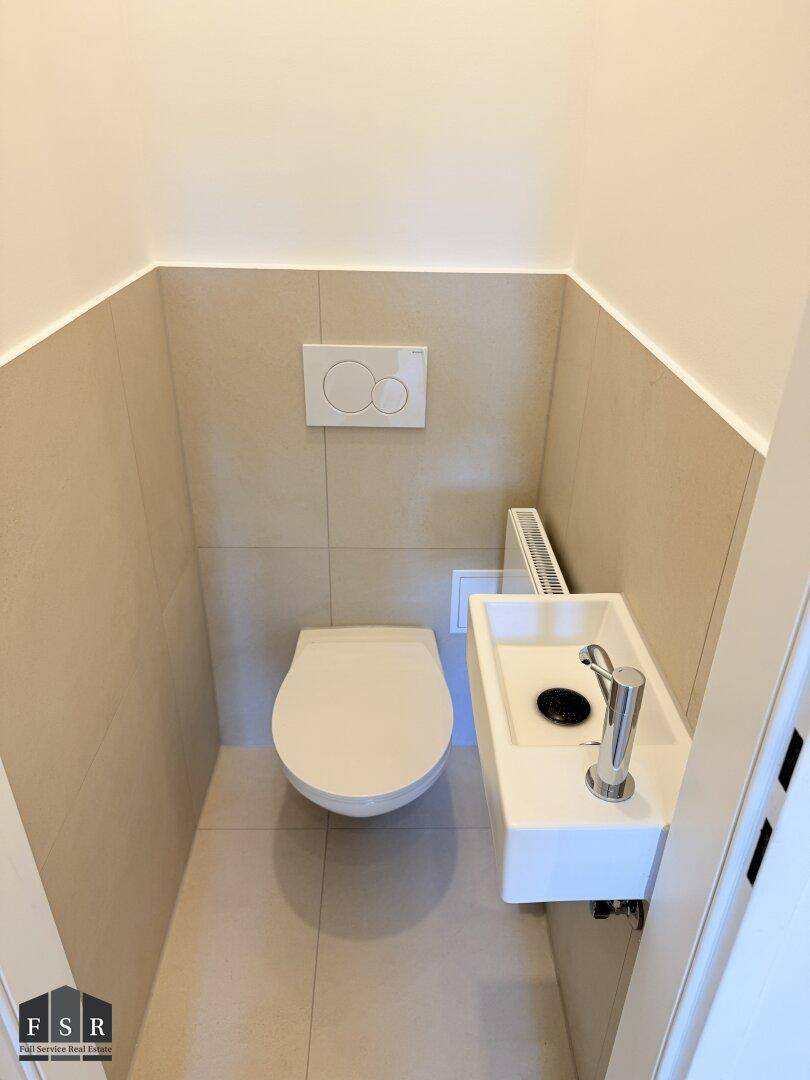 Kleines Gäste-WC mit wandhängendem WC und einem kompakten Handwaschbecken.