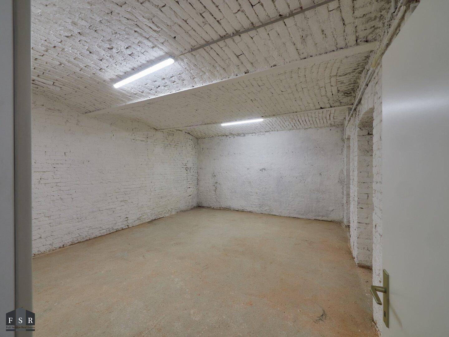 Geräumiger Kellerraum mit weiß gestrichenen Ziegelwänden und gewölbter Decke, ideal als Lager.