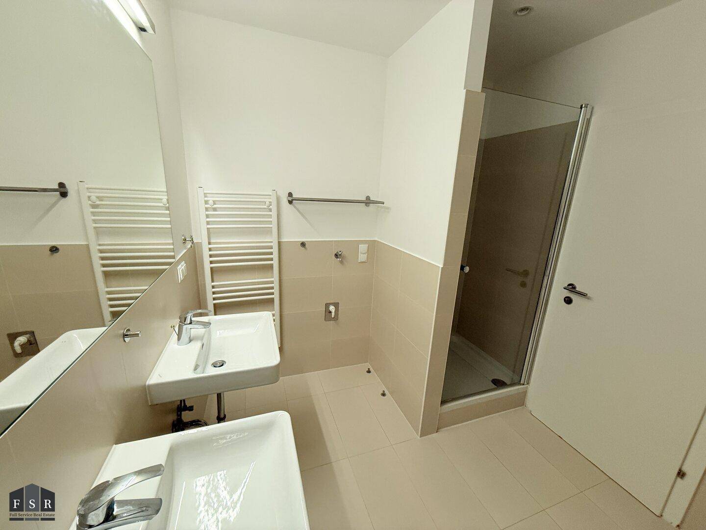 Modernes Badezimmer mit Doppelwaschbecken, Dusche und beheiztem Handtuchhalter.
