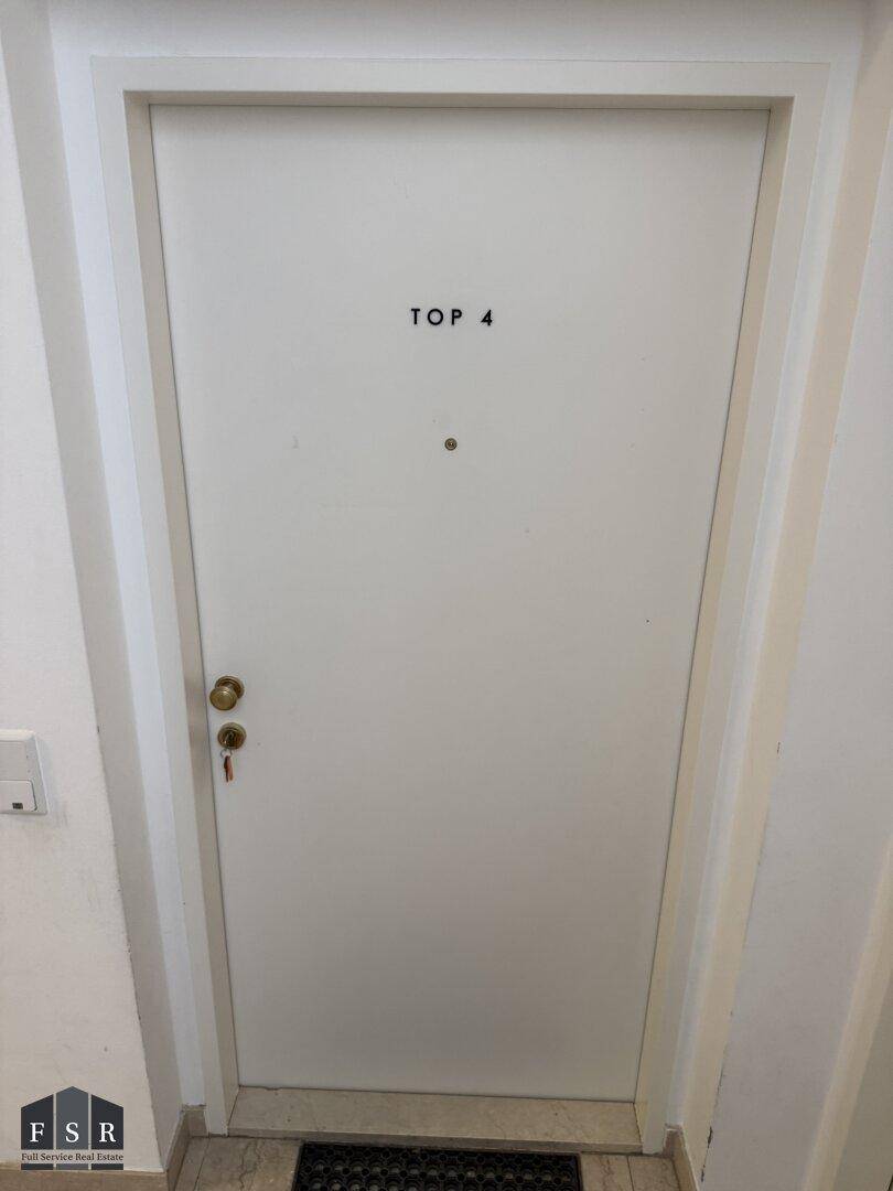 Eingangstür einer Wohnung mit der Nummer "TOP 4" und einem Türspion.