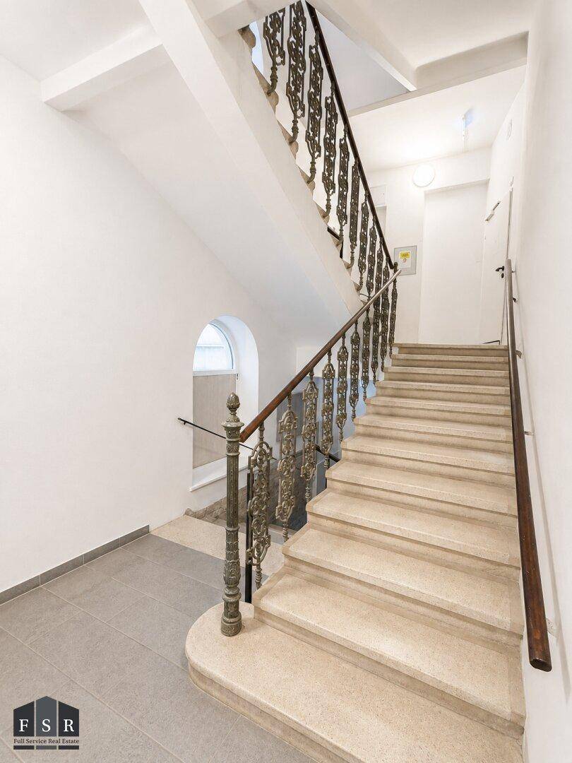 Elegantes Treppenhaus mit Steinstufen und kunstvoll geschmiedetem Geländer.