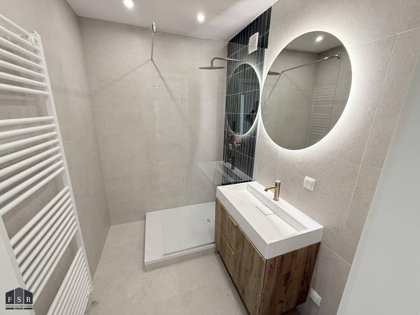 Modernes Badezimmer mit begehbarer Dusche, stilvollem Waschtisch und beleuchtetem Spiegel.