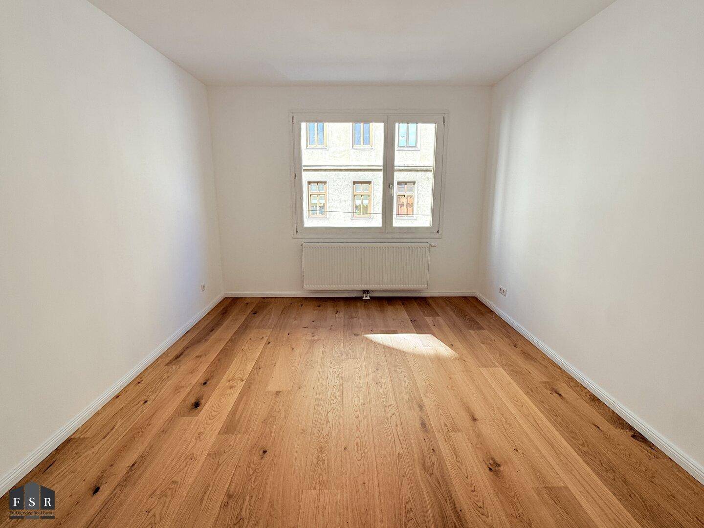 Leeres Zimmer mit neuem Parkettboden und weiß gestrichenen Wänden, ideal als Schlafzimmer.