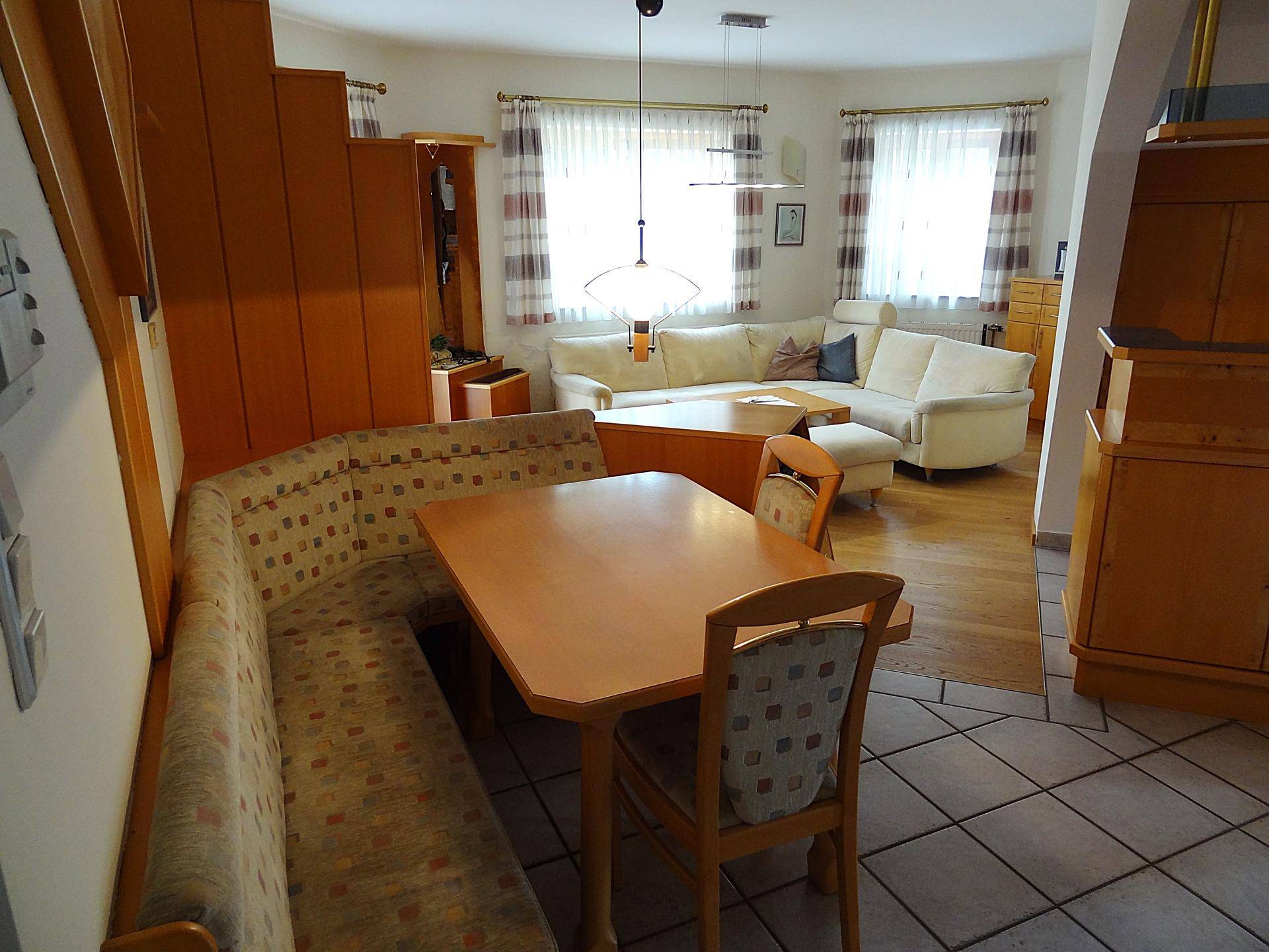 Offener Wohn- und Essbereich mit Eckbank, Holztisch und hellem Sofa.