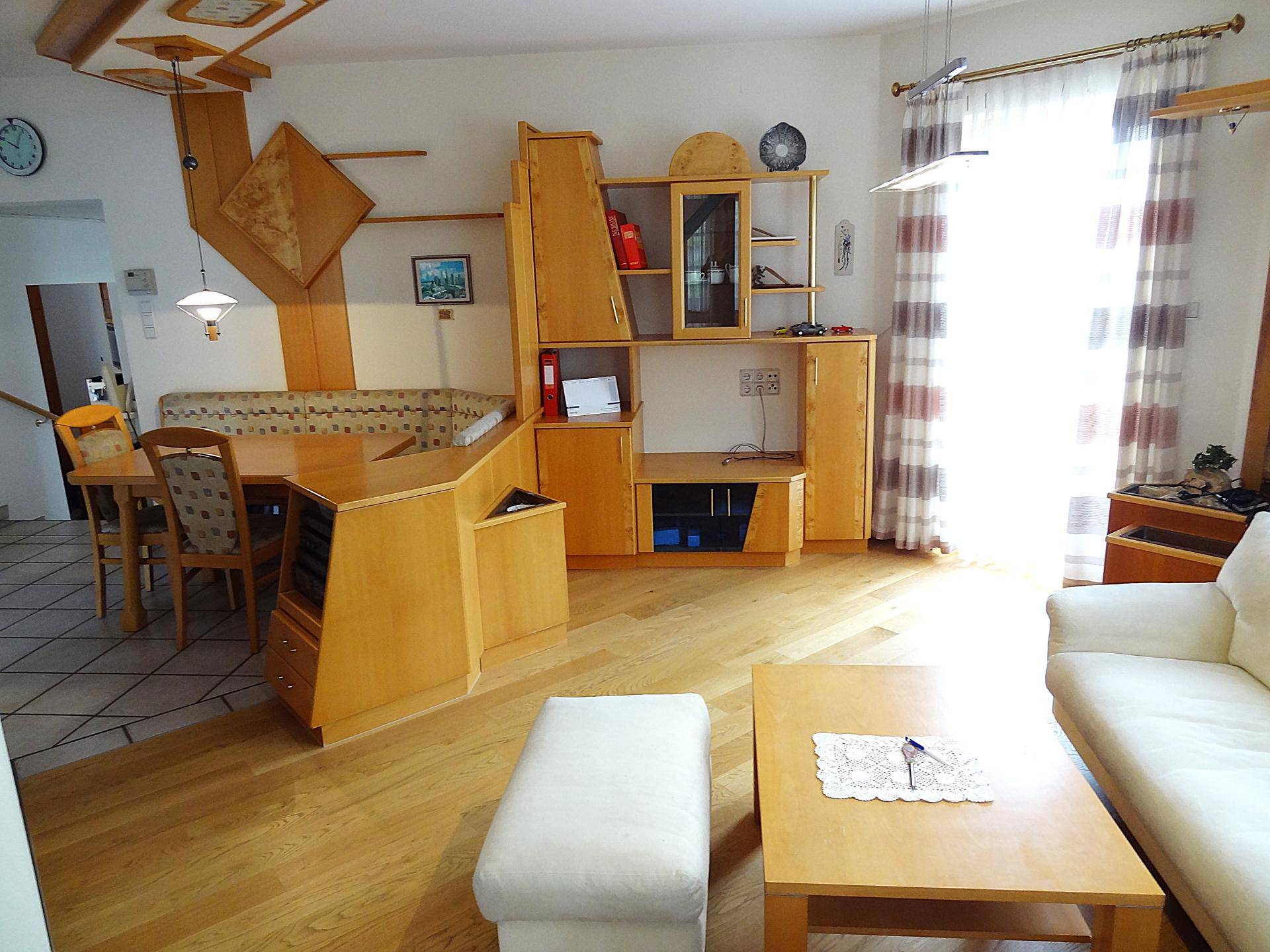 Heller Wohn- und Essbereich mit Holzmöbeln, Sofa und Blick auf den Essbereich.