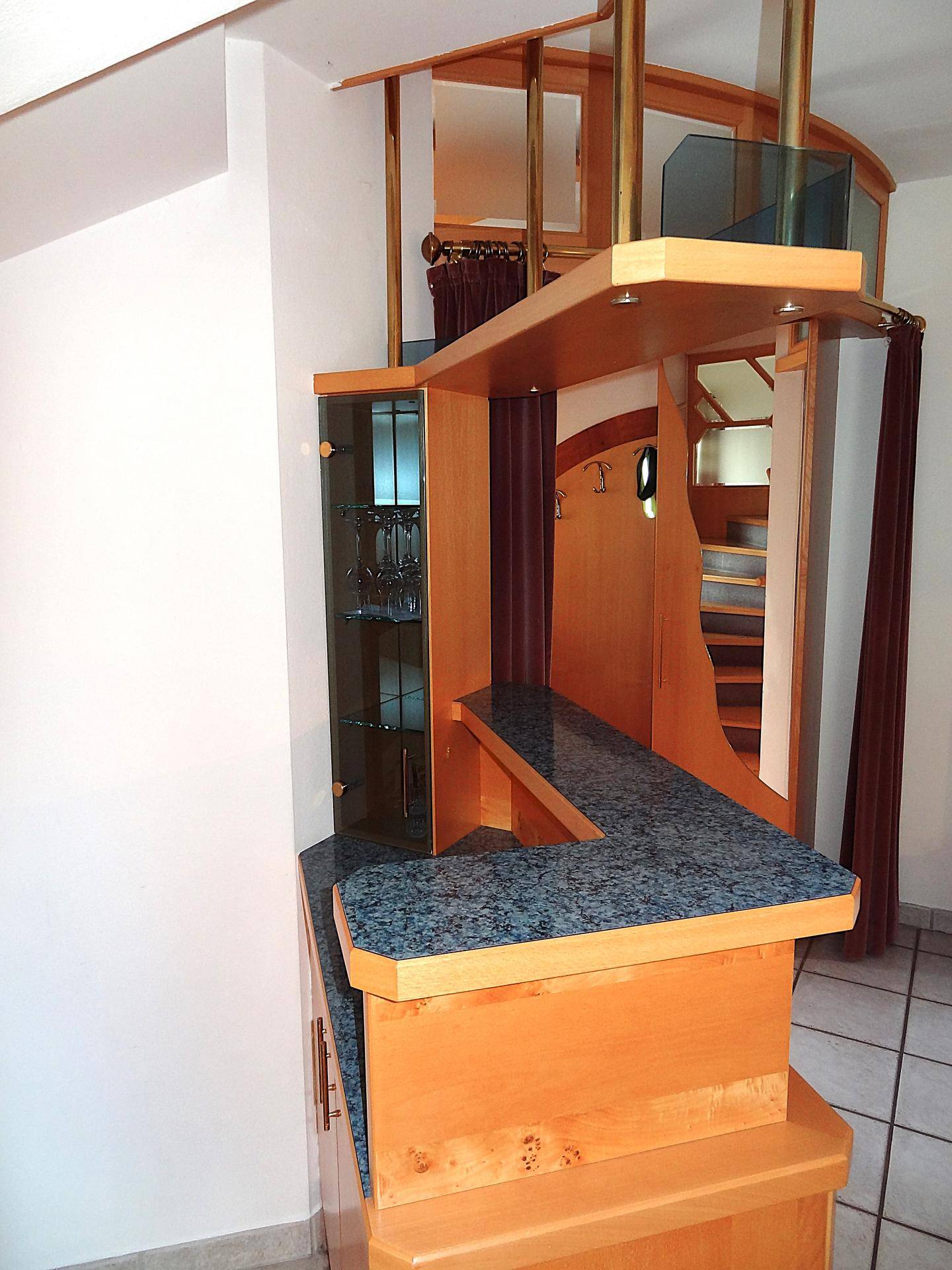 Hausbar mit Granitplatte und integriertem Glasschrank, angrenzend an den Wohnbereich.