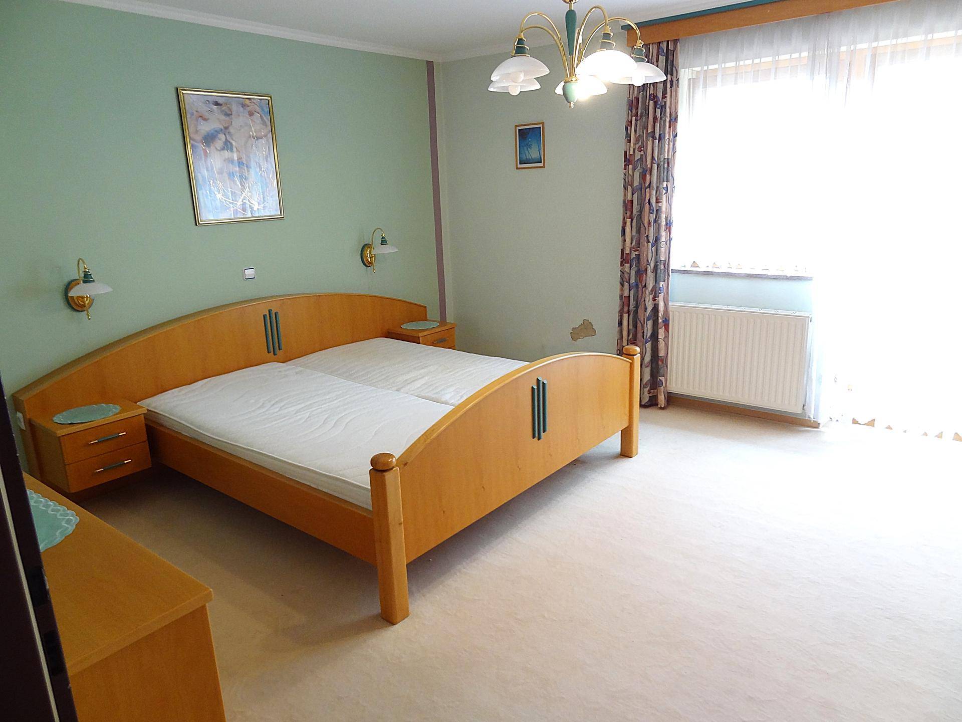 Helles Schlafzimmer mit Doppelbett, Nachttischen und grün gestrichenen Wänden.