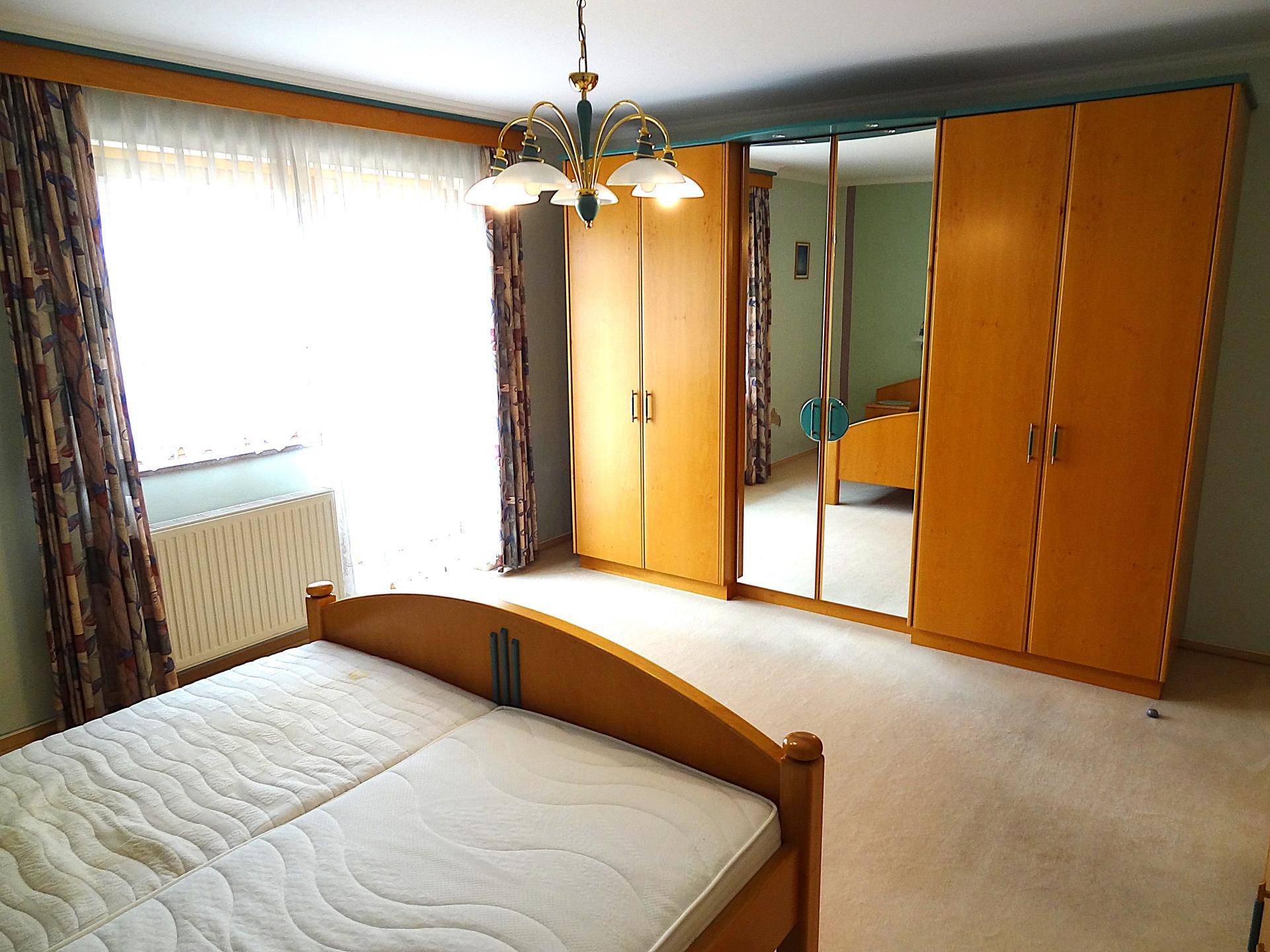 Geräumiges Schlafzimmer mit Doppelbett, großem Spiegelschrank und viel Tageslicht.