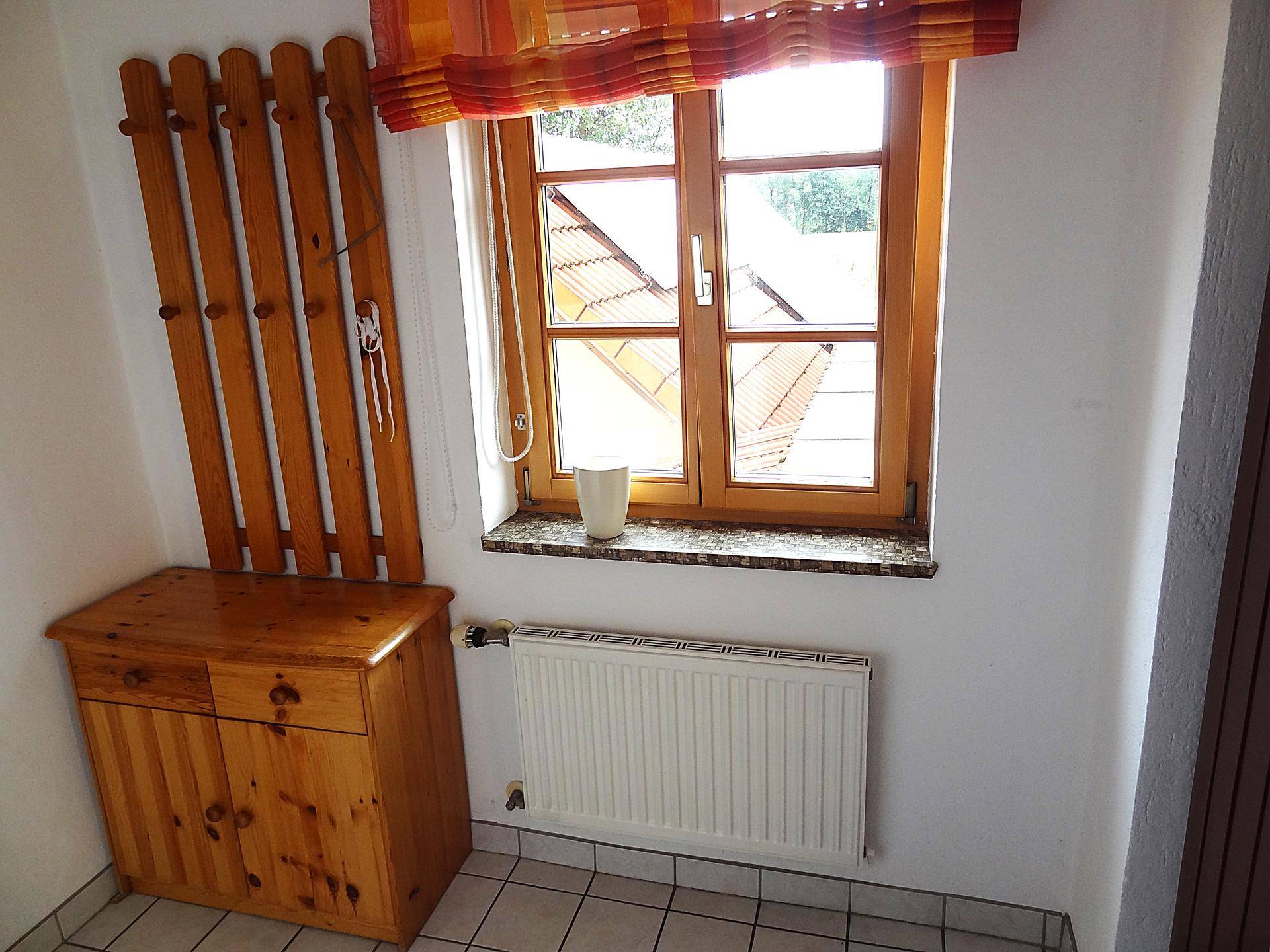 Gemütlicher Eingangsbereich mit Holzmöbeln, Fenster und Heizkörper.