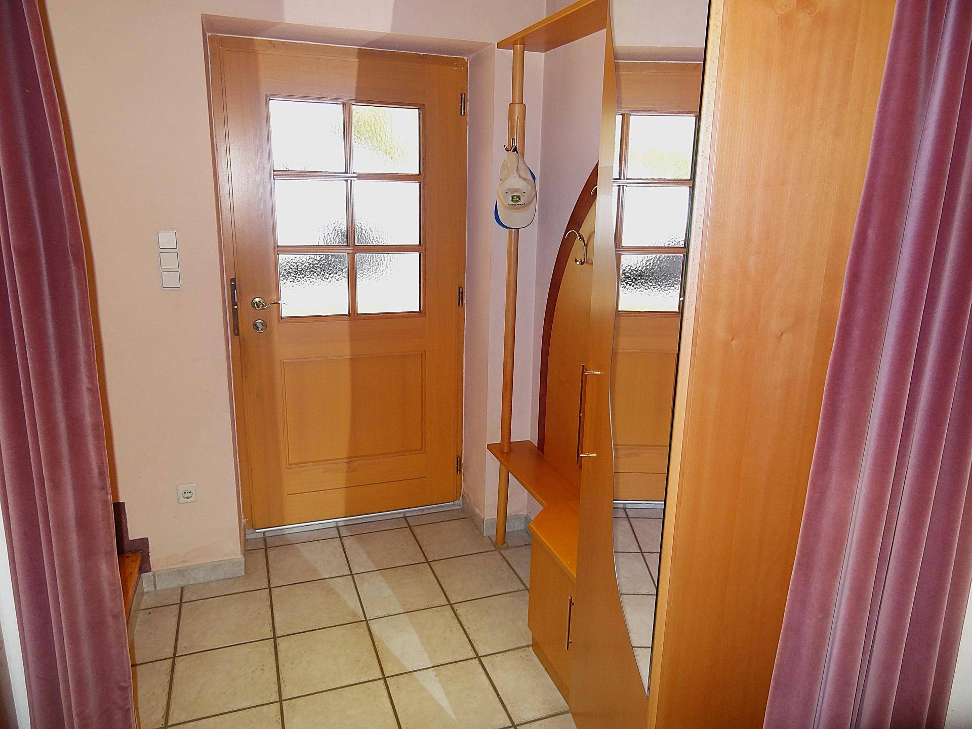 Eingangsbereich mit Garderobe, Spiegel und Holztür.